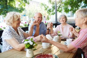 Group of seniors holding by hands during tea time