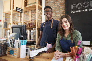 Portrait Of Male And Female Owners Of Sustainable Plastic Free Grocery Store Behind Sales Desk