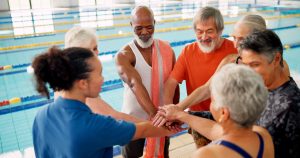 Swimming pool, senior people and huddle of group for learning, exercise and training together indoo.