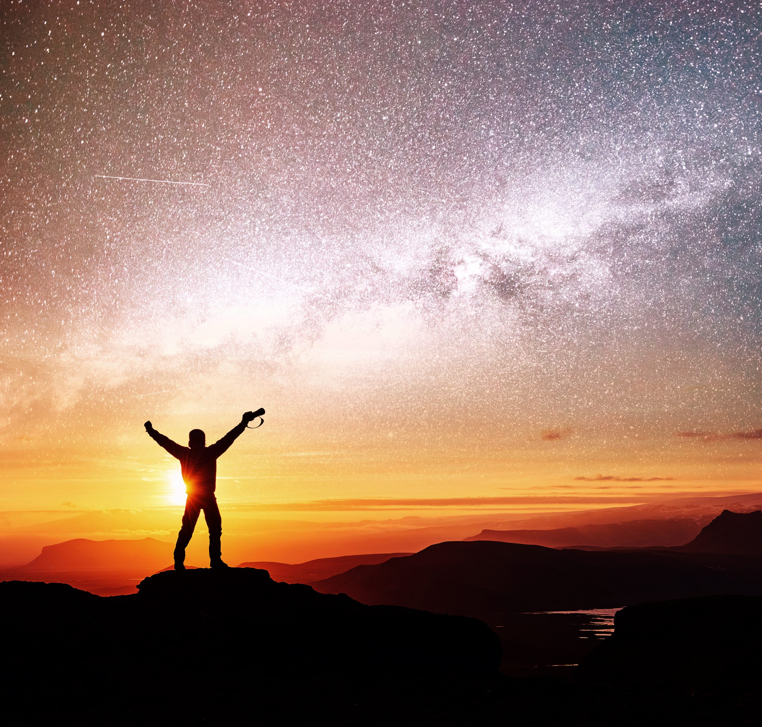 Silhouette of woman is standing on top of mountain and pointing to The milky way before sunrise and enjoying with colorful night sky.